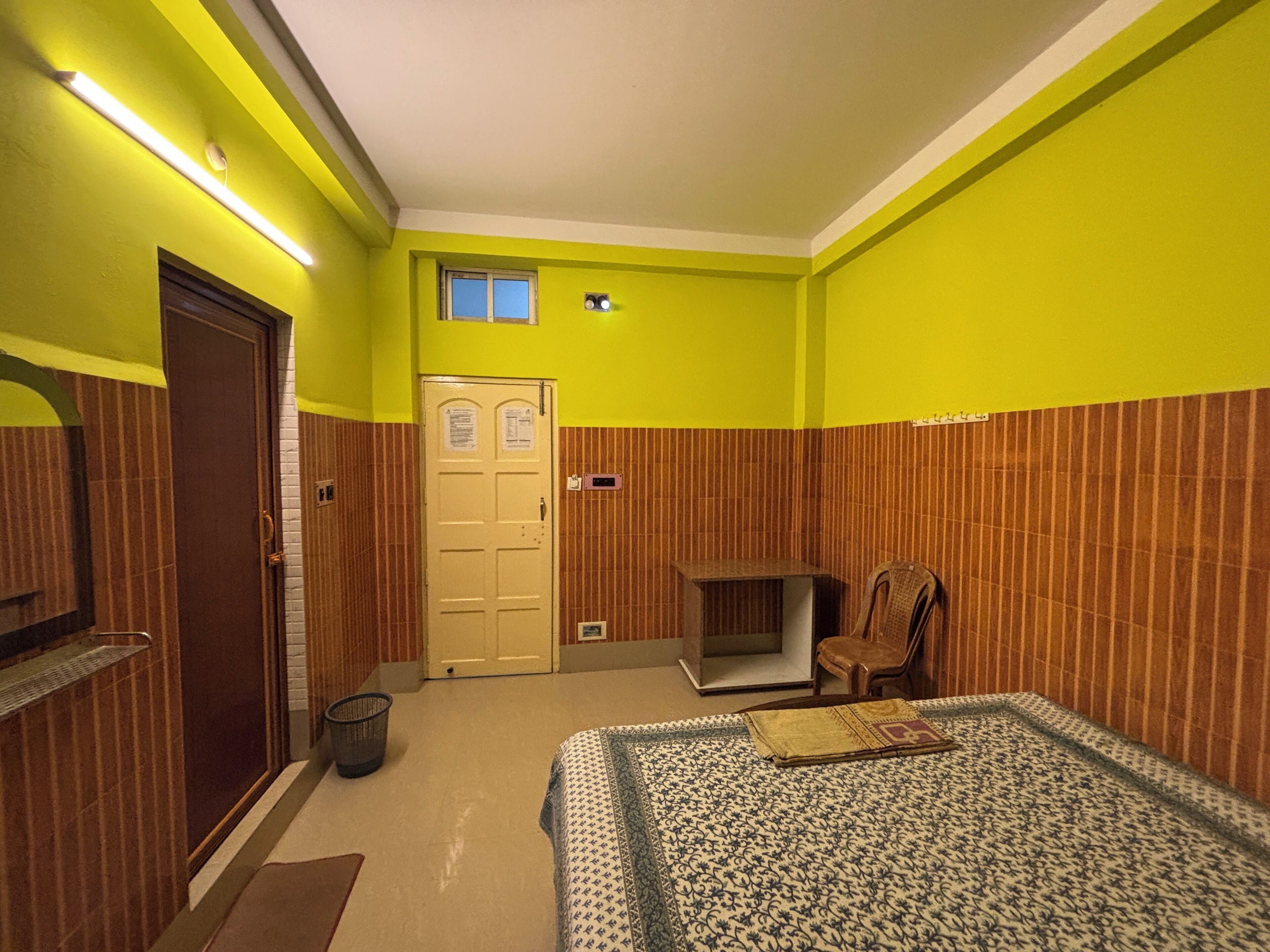 Une pièce comprenant un lit, une chaise, une petite table, une porte et une fenêtre.
