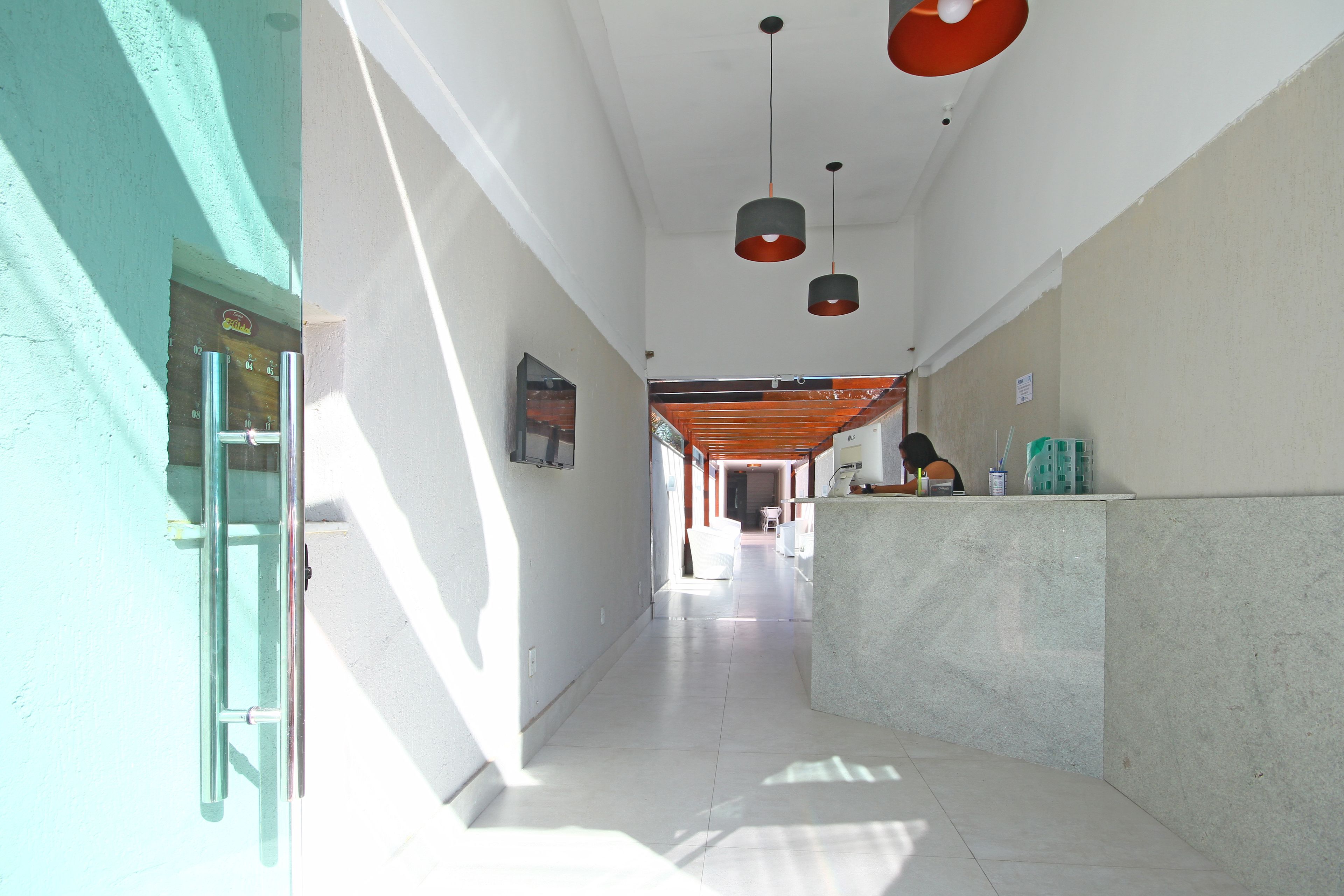 A hallway with a reception desk, a staircase, and pendant lighting.