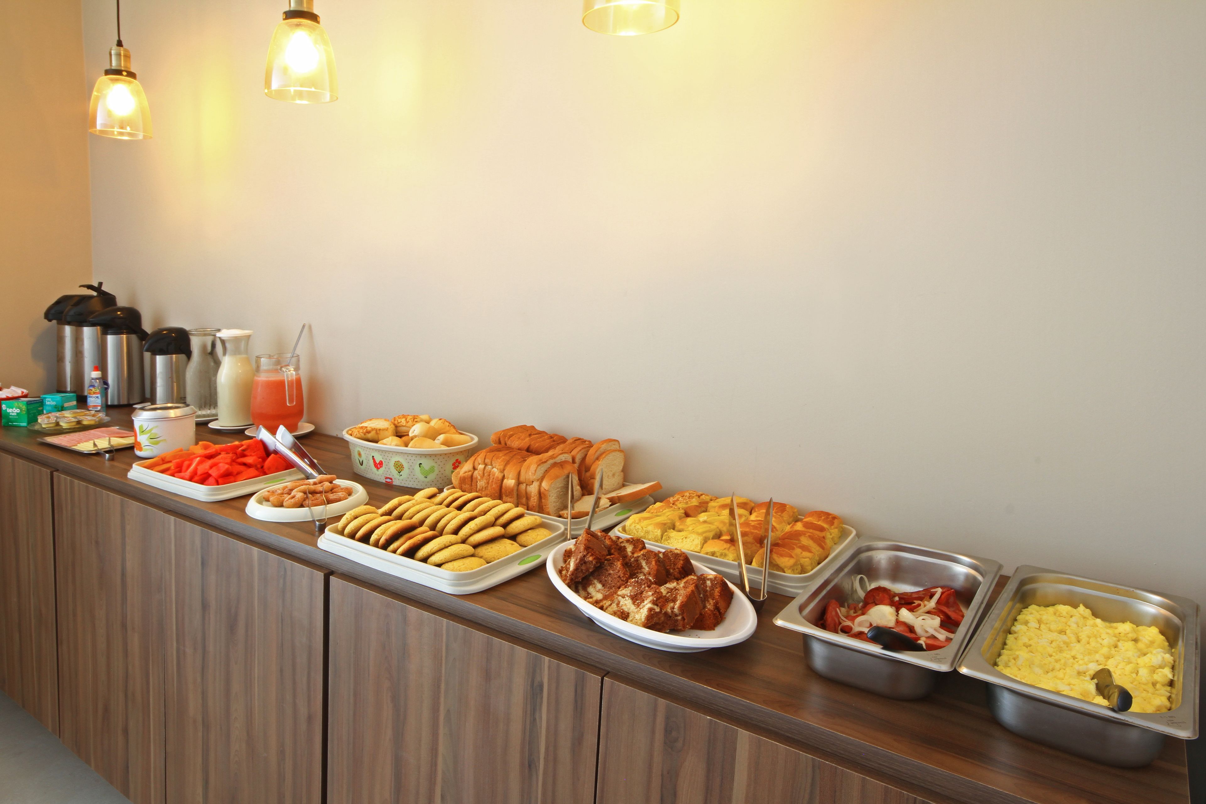 Un bufé con diferentes opciones de comida, incluyendo pan, pasteles y frutas.