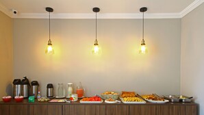 A buffet setup with various food items and beverages, including a coffee maker, thermos, and juice. - MDJ Pousada (Cabo Frio)