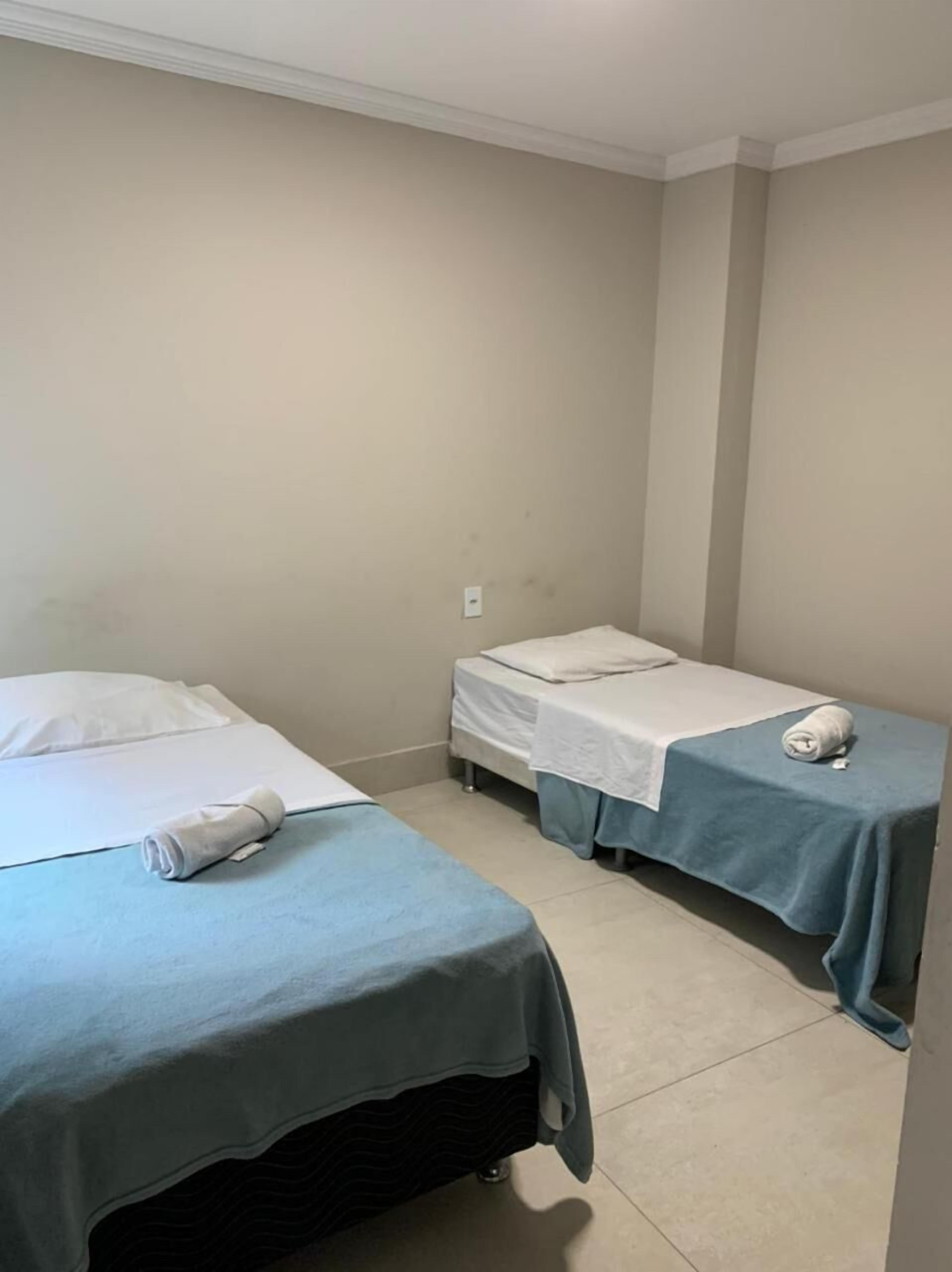 A room with two beds, each with a blue bedspread and white pillows.
