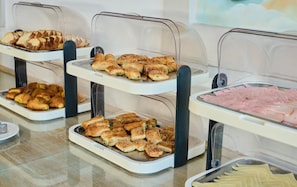 Un bufé con diversos alimentos, incluyendo pasteles y embutidos.