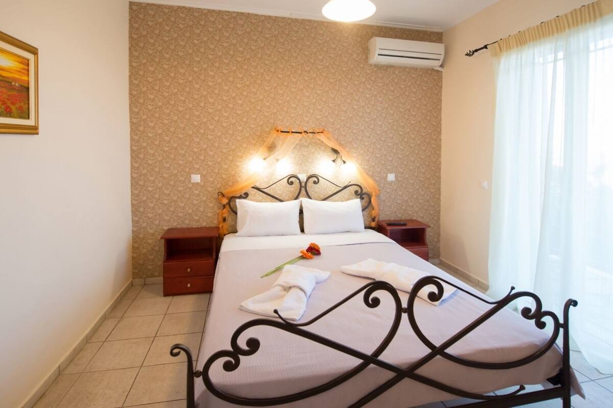 A neatly arranged bedroom with a bed, bedside tables, a nightstand, and a wall-mounted air conditioner.