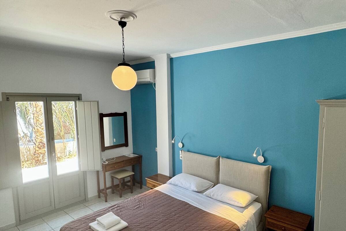 Un dormitorio con cama, mesitas de noche, un escritorio y una silla.