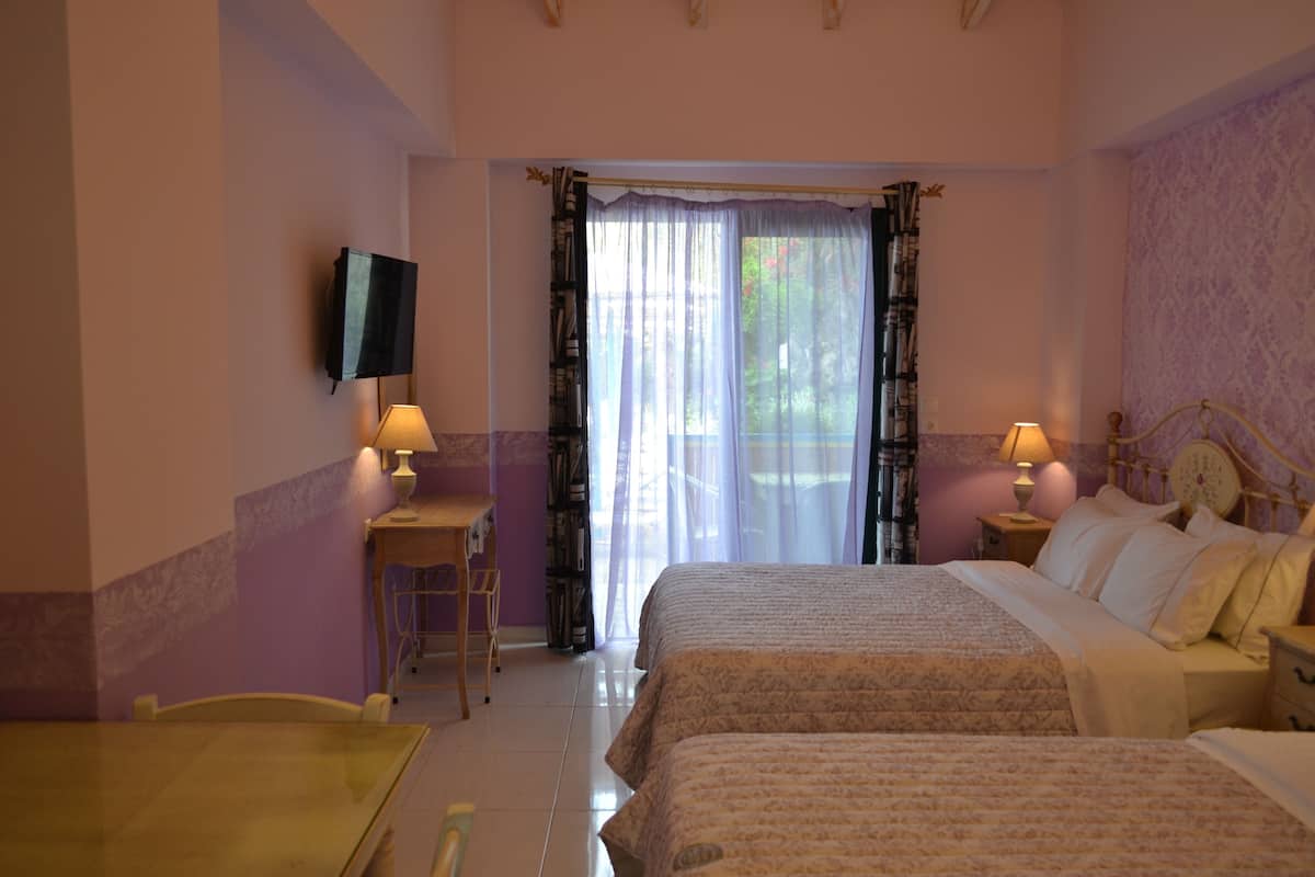 Un dormitorio con dos camas, televisión, escritorio con lámpara y ventana con cortinas.