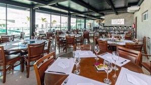 Un restaurante amplio con varias mesas y sillas, ventanas grandes que ofrecen vistas al exterior, y un diseño de techo moderno.