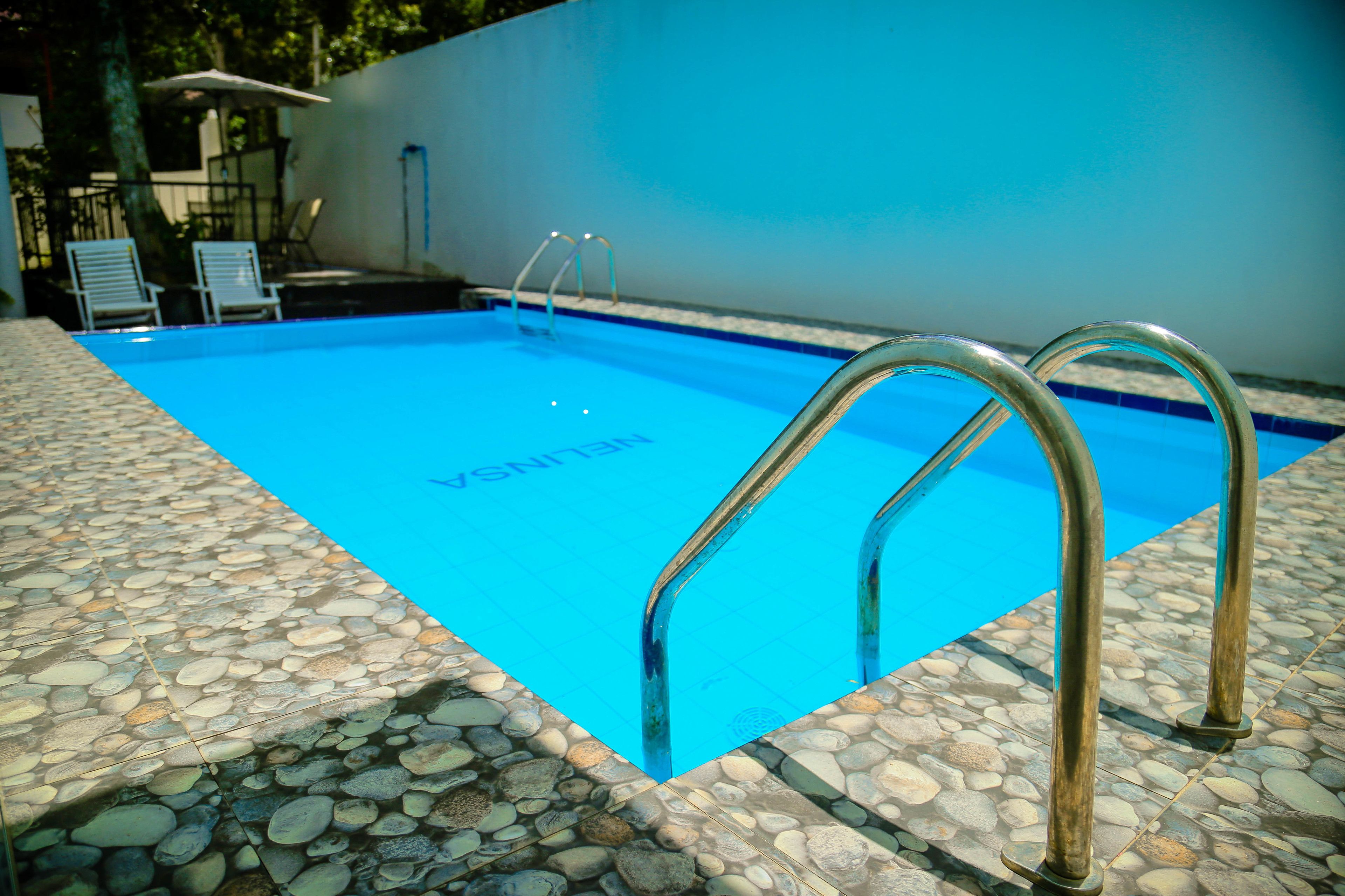 A swimming pool with a stone deck and metal pool ladder.