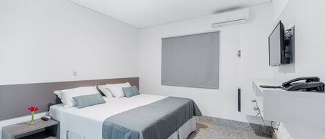 A modern hotel room with a bed, bedside table, and a TV mounted on the wall.