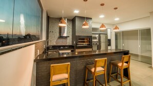 A modern kitchen with a large island, pendant lights, and wooden bar stools. - Prime Hotel Ponta Porã (Ponta Pora)
