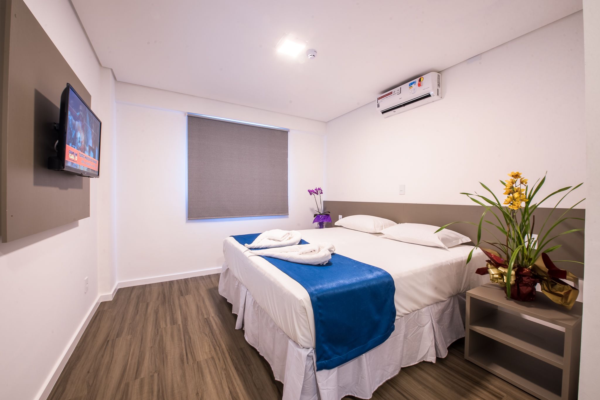 A hotel room with two beds, a TV, an air conditioning unit, and a window with a view.