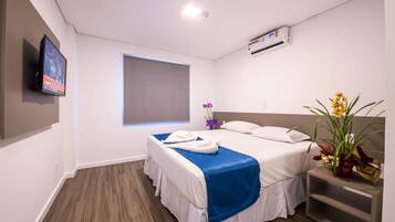 A hotel room with two beds, a TV, an air conditioning unit, and a window with a view.