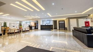 A modern hotel lobby with a reception desk, seating area, and a polished marble floor. - Prime Hotel Ponta Porã (Ponta Pora)