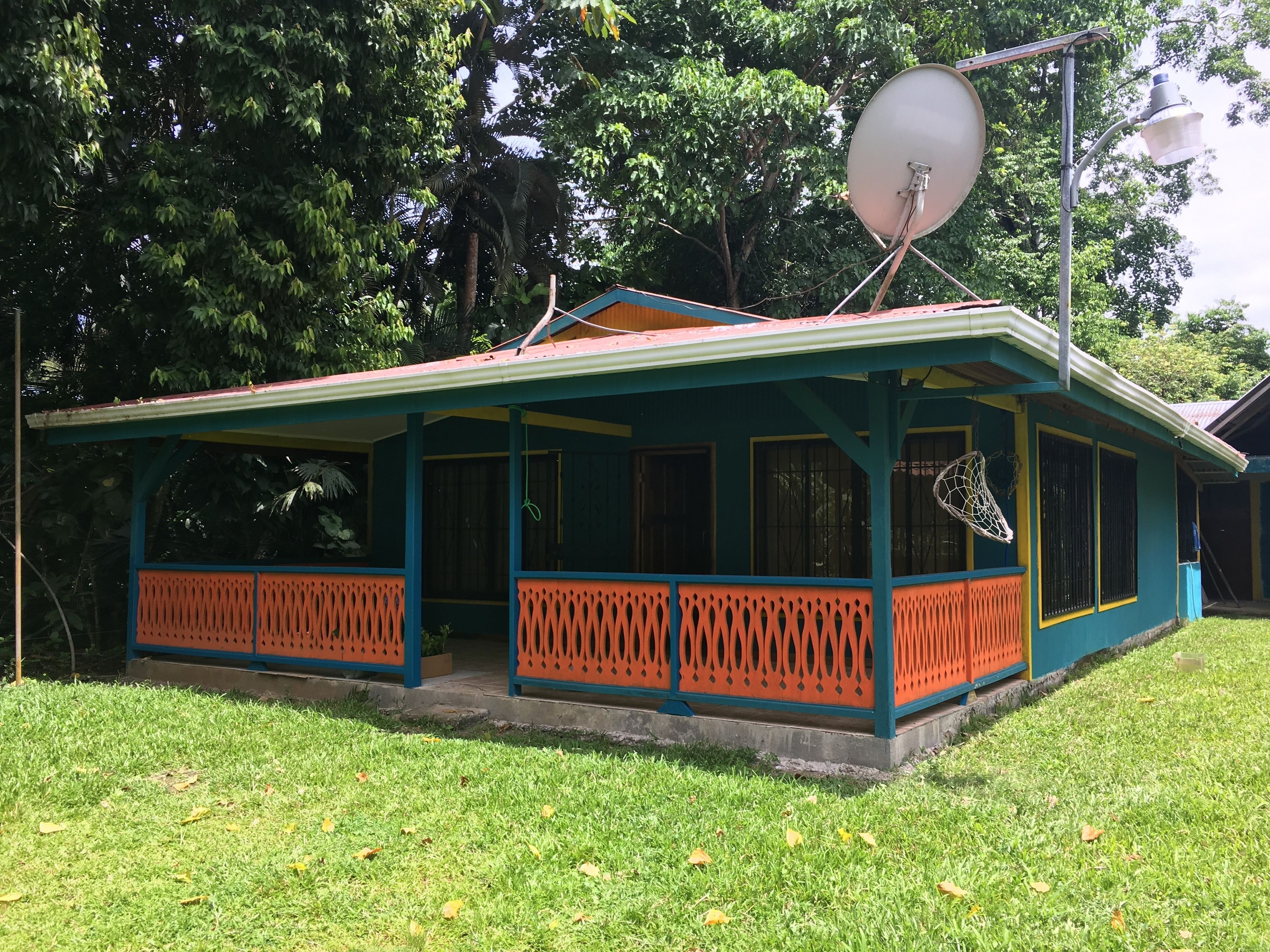 A house with a porch, a satellite dish, and a basketball hoop.