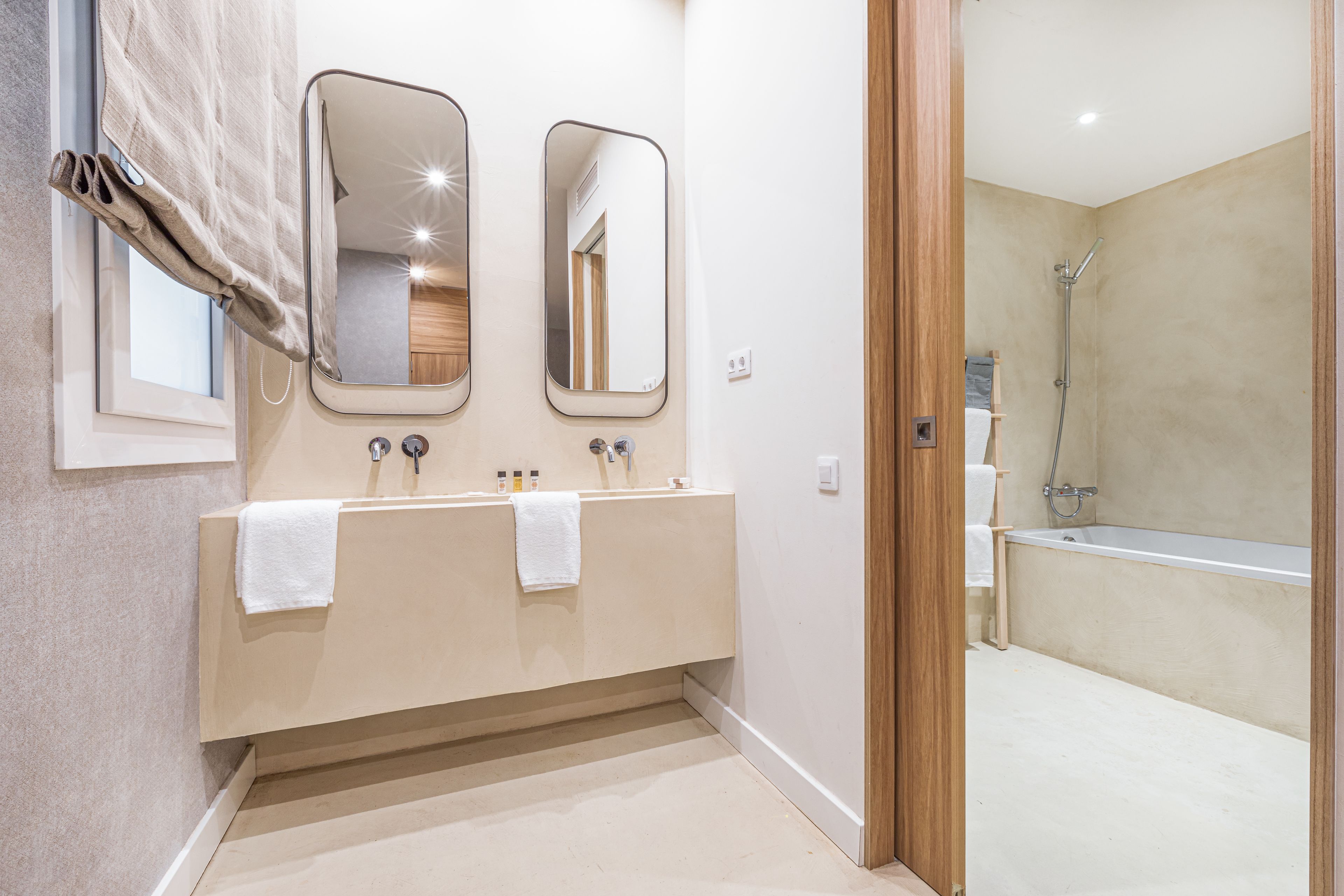 Un baño moderno con lavamanos doble, dos espejos y cabina de ducha.