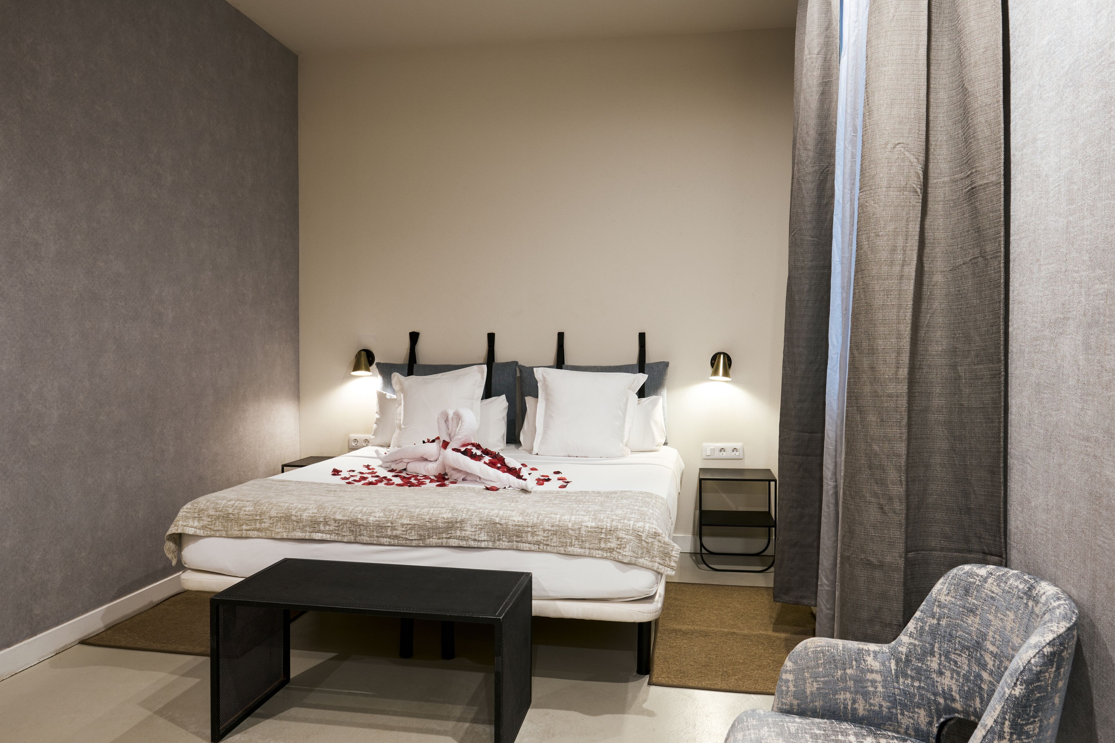 Une chambre d’hôtel moderne avec un grand lit, des tables de chevet, une petite table et une chaise.