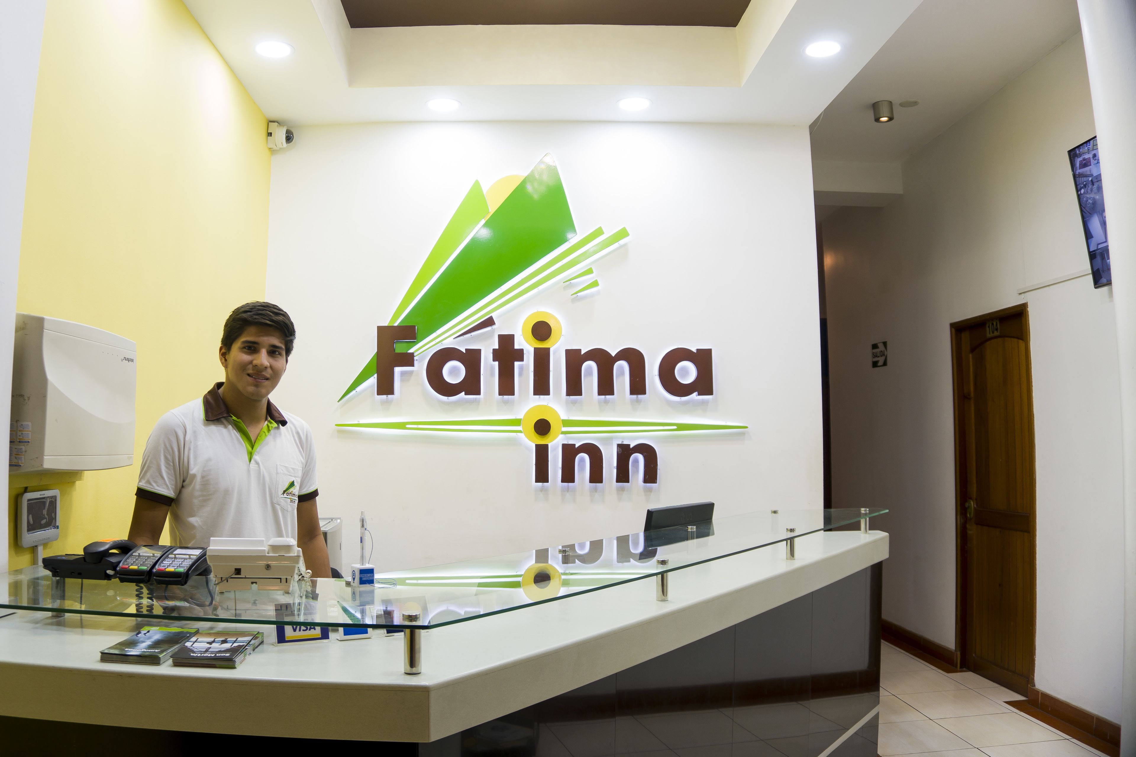 A reception desk with a sign reading "Fatima inn" and a man standing behind it.