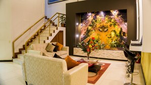 Una sala de estar moderna con una escalera, un sofá, una mesa de centro y un muro decorativo con una escena nocturna.