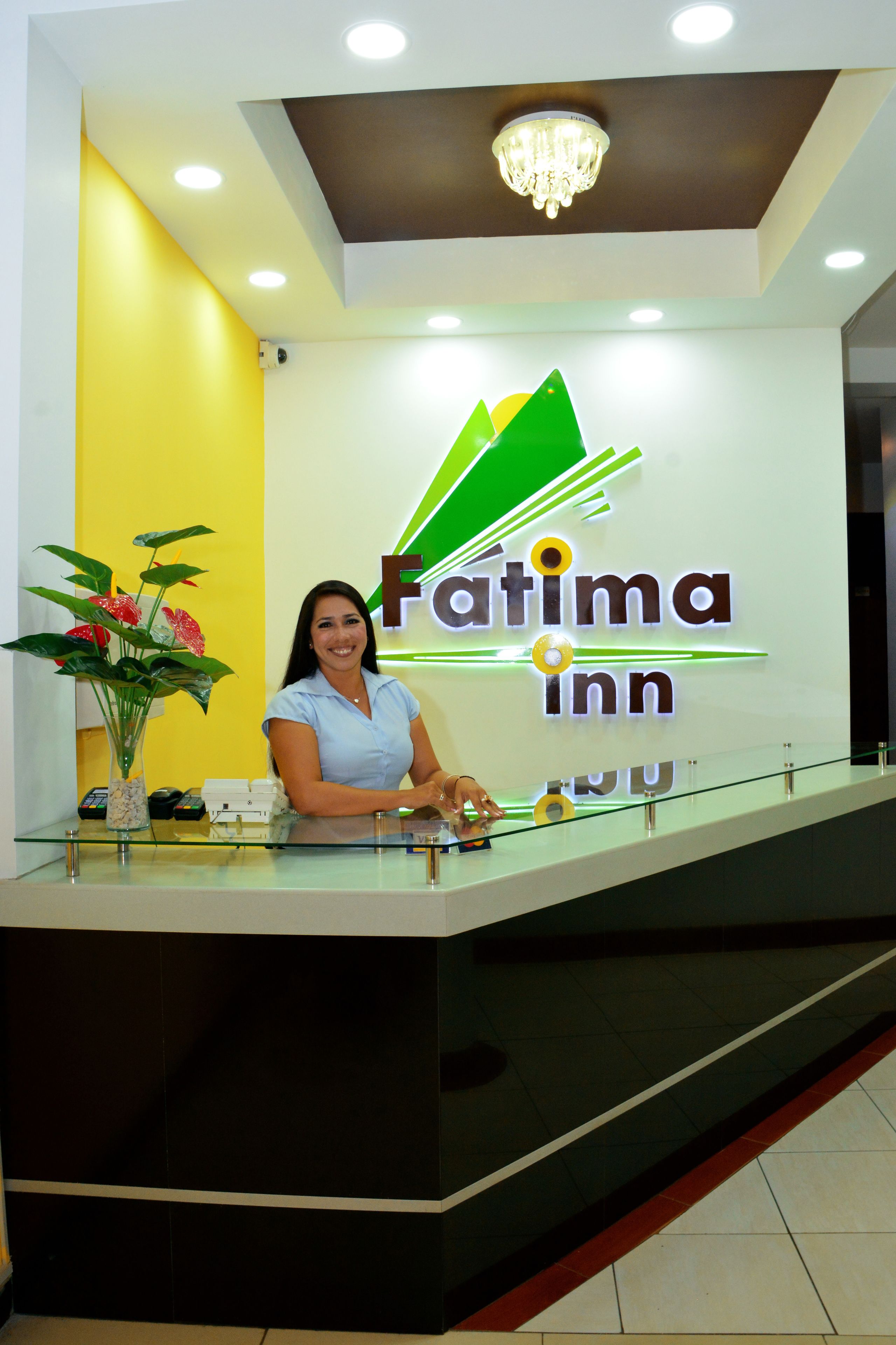 A reception desk at Fatima Inn with a modern design, a chandelier, and a vase with flowers.