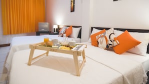 Habitación de hotel con cama, mesita de noche con lámpara, bandeja con alimentos para el desayuno y obras de arte en las paredes.