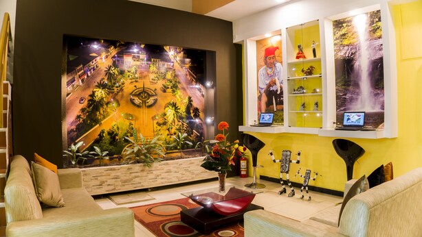 Un vestíbulo moderno con un mural grande en la pared, un mostrador de recepción y una zona de estar con sofás y una mesa de centro.