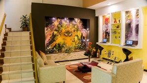 Una sala de estar moderna con una escalera, un mural grande en la pared y una zona de estar con sofás y una mesa de centro.