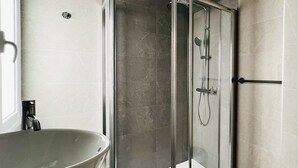 A modern bathroom with a glass-enclosed shower, a freestanding bathtub, and a sink with a faucet.