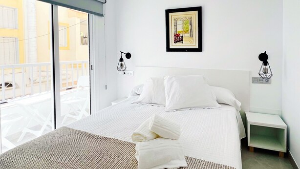 A hotel room with a bed, a view of the outside balcony, and a framed picture on the wall.