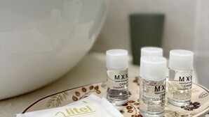 A white bowl, four bottles of shampoo, and a sachet of shampoo on a patterned tray.