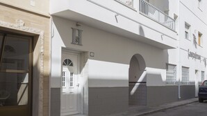 A white building with a balcony, a door with a number, and a small window.