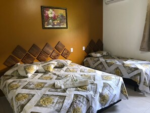 Una stanza con due letti, ognuno con copriletto a motivi floreali e testiere in legno.
