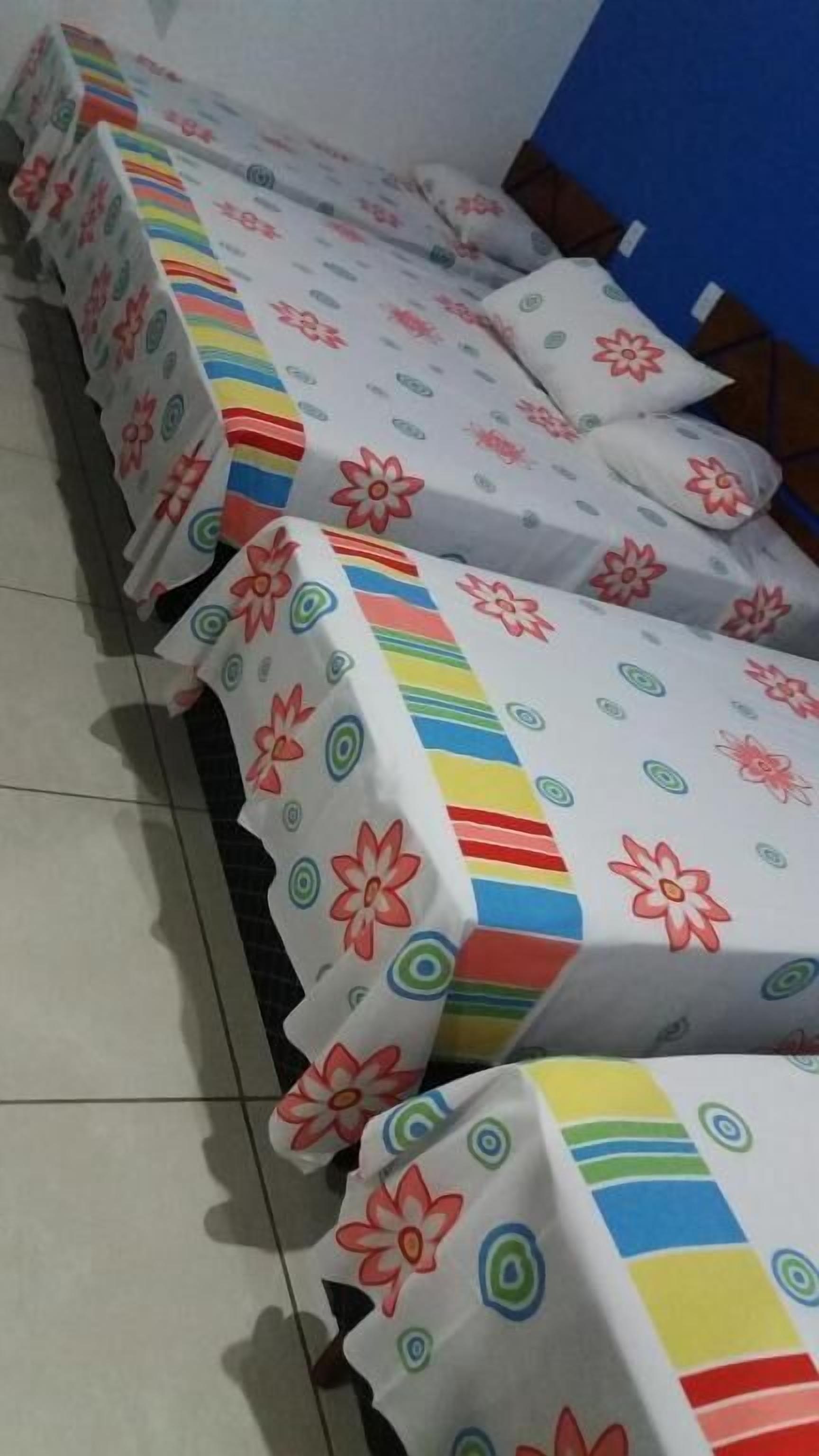 Varias camas con ropa de cama floral y a rayas en una habitación de hotel.