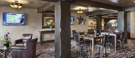 A restaurant with a large wooden beam ceiling, a TV displaying a weather forecast, and a carpeted floor.