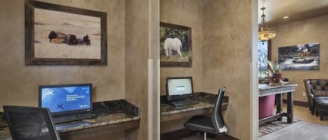 Un espace d’accueil comprenant deux postes de travail équipés d’ordinateurs, un coin salon avec un fauteuil et une table à manger avec une chaise.