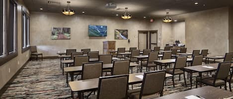 A conference room with multiple tables and chairs, large windows, and artwork on the walls.
