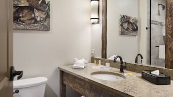 A bathroom with a toilet, sink, and mirror. There are towels and toiletries on the counter.