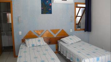 Una habitación con dos camas individuales, un cabecero de madera, un cuadro, un equipo de aire acondicionado y una ventana con cortinas.