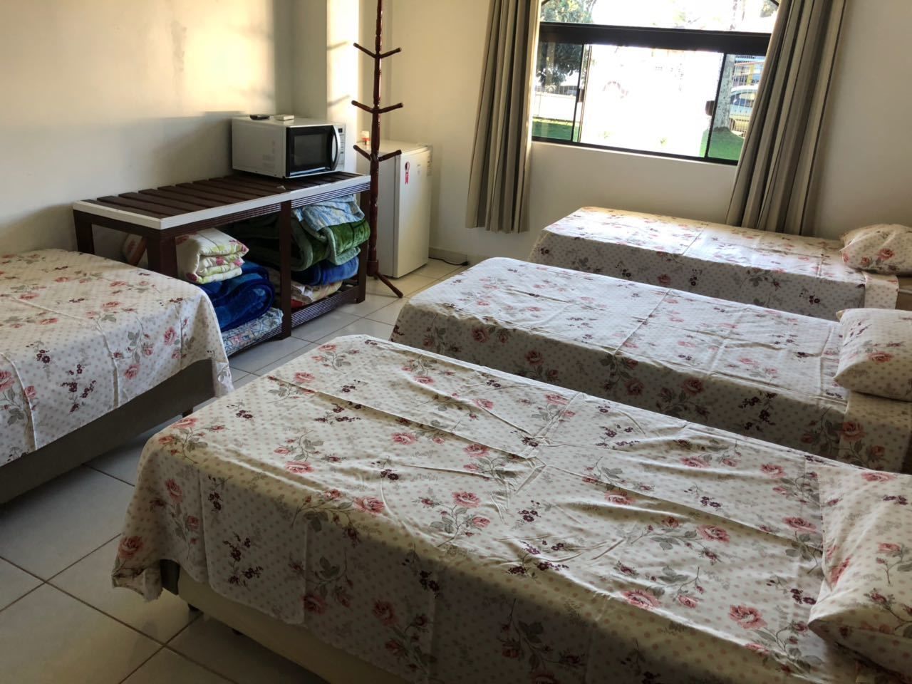 Une chambre avec quatre lits, une petite table avec un micro-ondes et un radiateur.