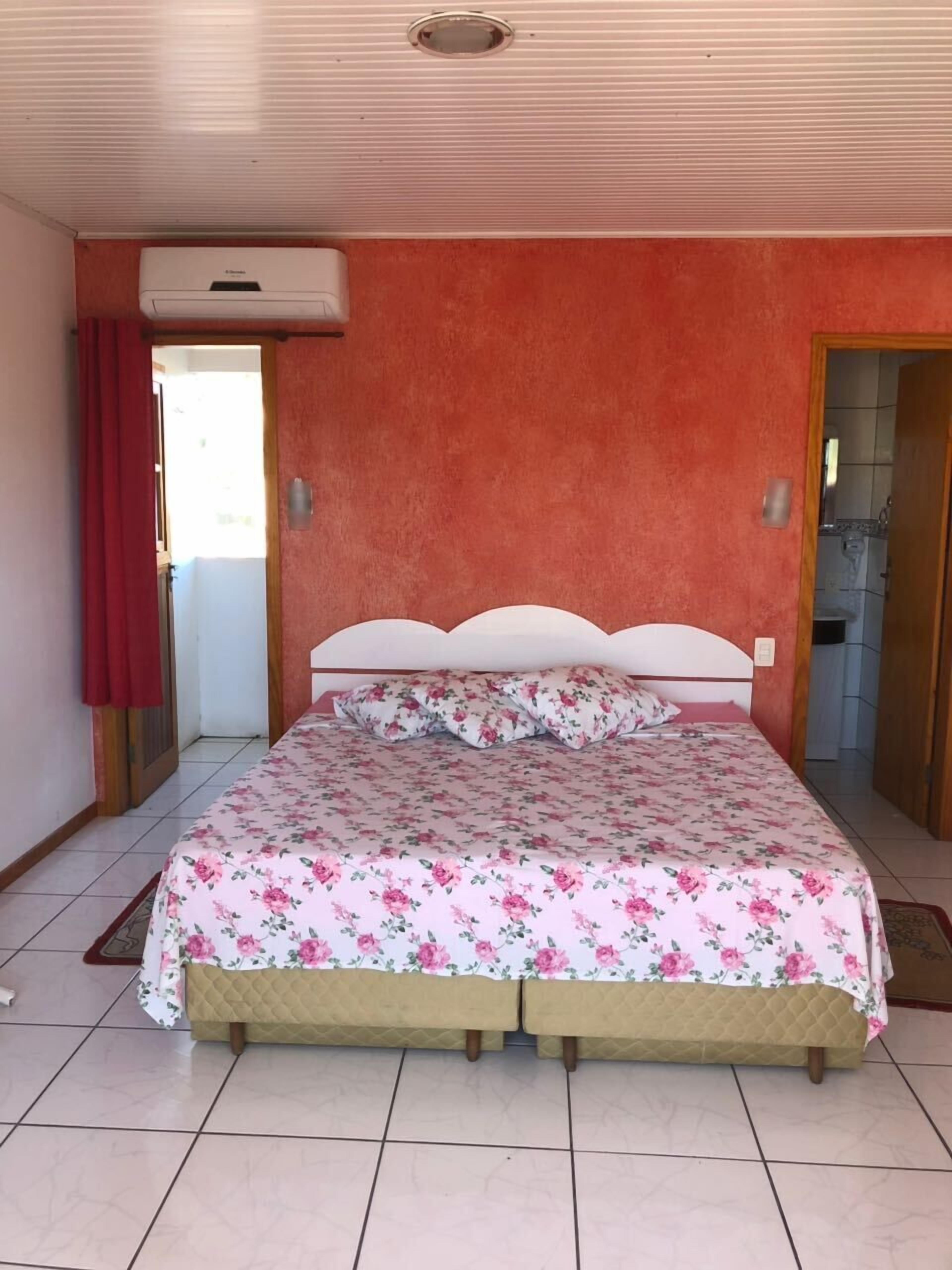 A bedroom with a bed, a red curtain, and a ceiling fan.