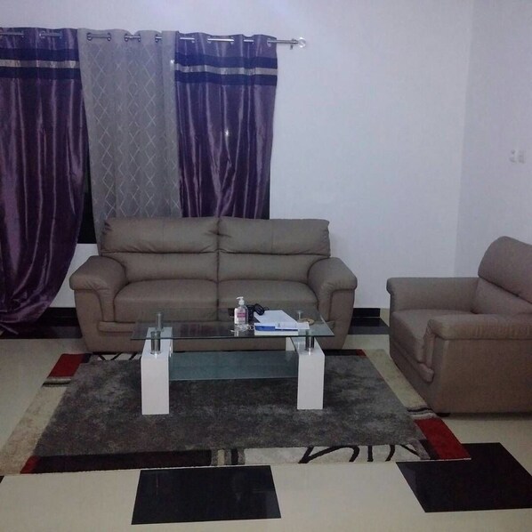 A living room with two sofas, a glass coffee table, and a patterned rug.