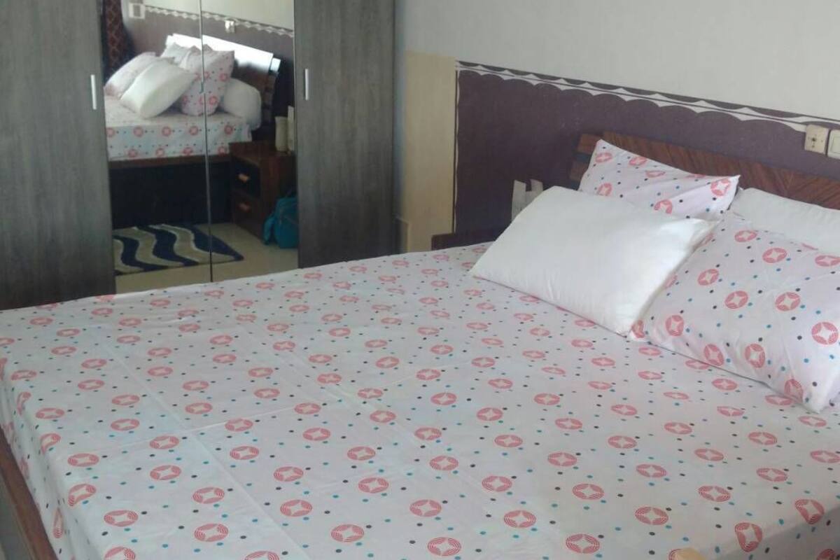 A hotel room with a bed, a wardrobe, and a mirror.