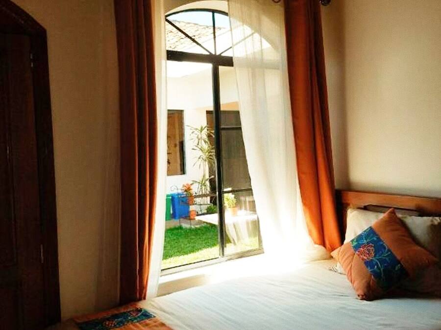 Una habitació d'hotel amb llit, cortines i vista a l'exterior.