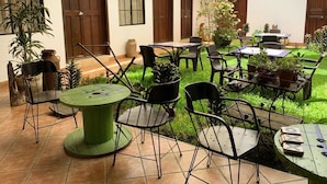 Un patio con mobiliario exterior, plantas en macetas y piso de baldosas.