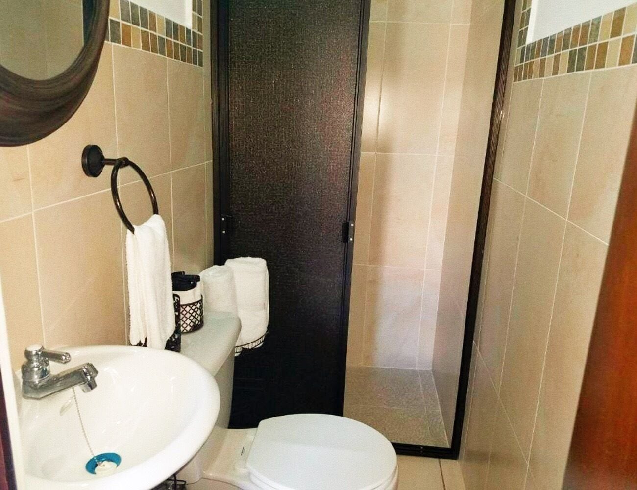 Un baño pequeño con un lavamanos blanco, un inodoro y una puerta oscura.