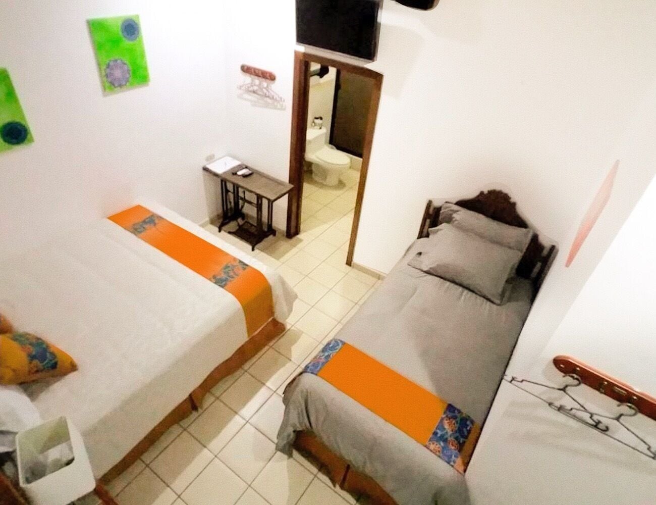 A small, compact room with two single beds, a small table, and a television.