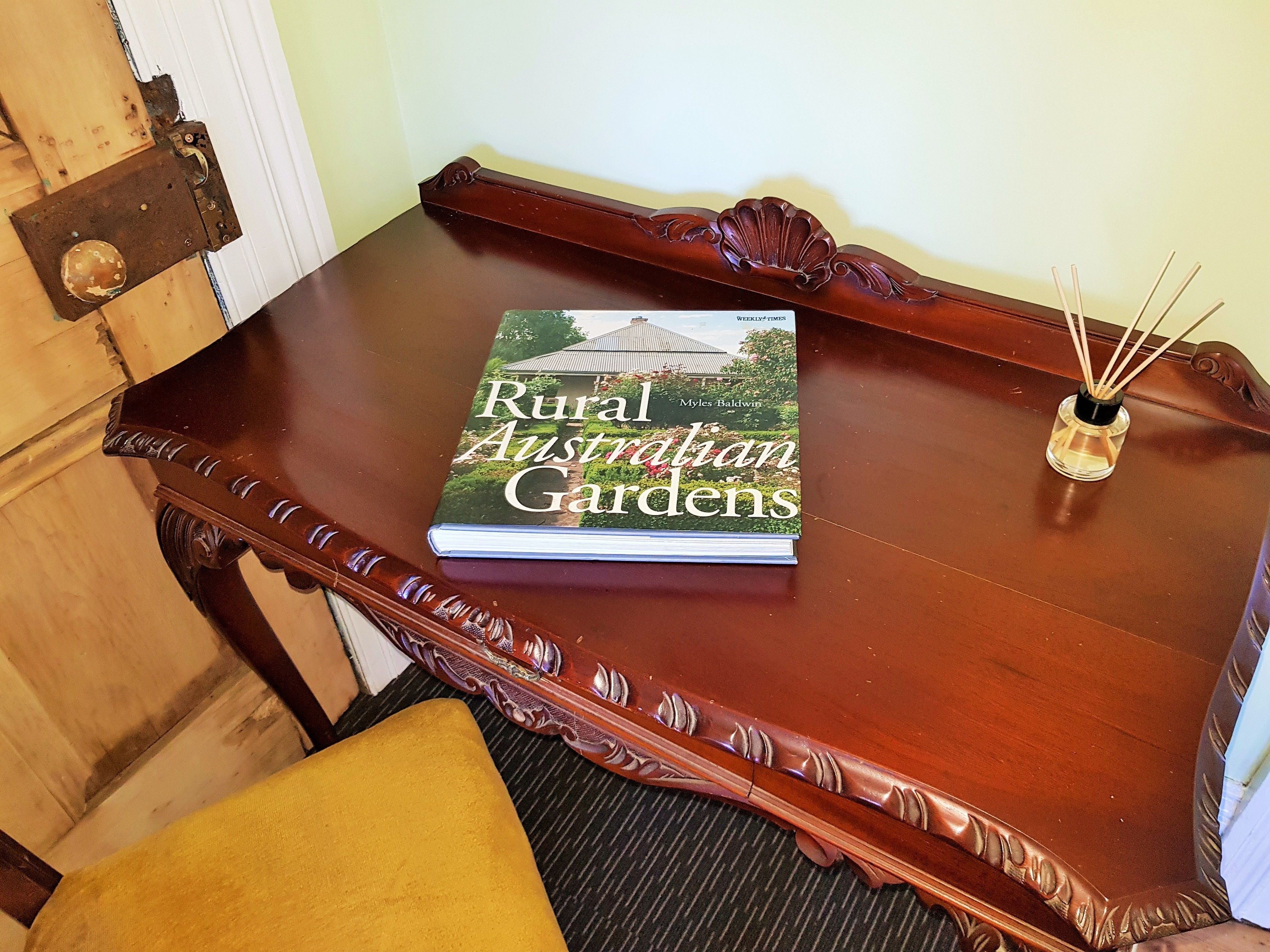 A book titled 'Rural Australian Gardens' on a wooden table with a decorative edge.