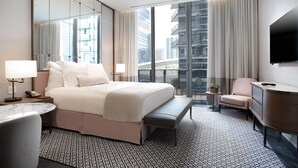 Une chambre d’hôtel moderne dotée d’un grand lit, d’un bureau, d’une chaise, d’une télévision et d’un balcon offrant une vue sur la ville.