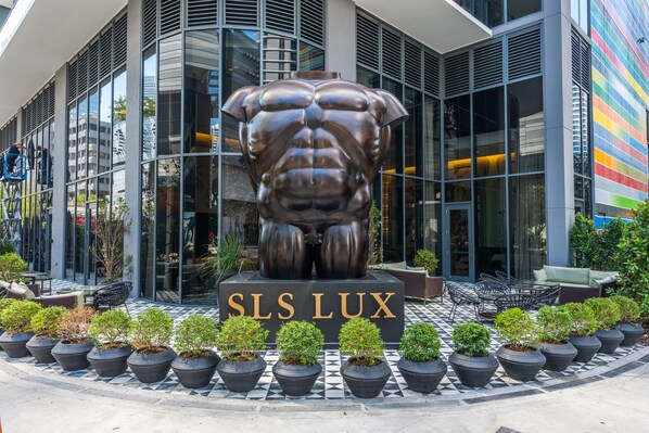 Un bâtiment moderne, devant lequel se trouve une grande sculpture en bronze représentant un torse musclé.