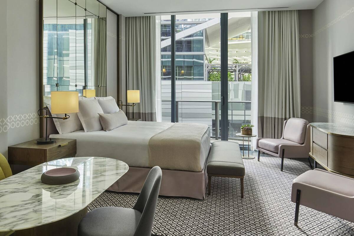 Ein modernes Hotelzimmer mit einem großen Bett, einem Schreibtisch mit Stuhl, einer Couch und einem Fernseher.