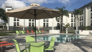 Un espace aménagé au bord de la piscine, avec des chaises longues, une table et des parasols.