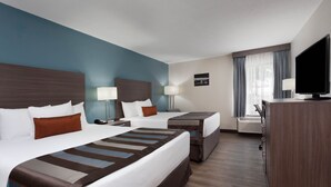 Une chambre d’hôtel avec deux lits, une télévision, un bureau et une fenêtre avec des rideaux.